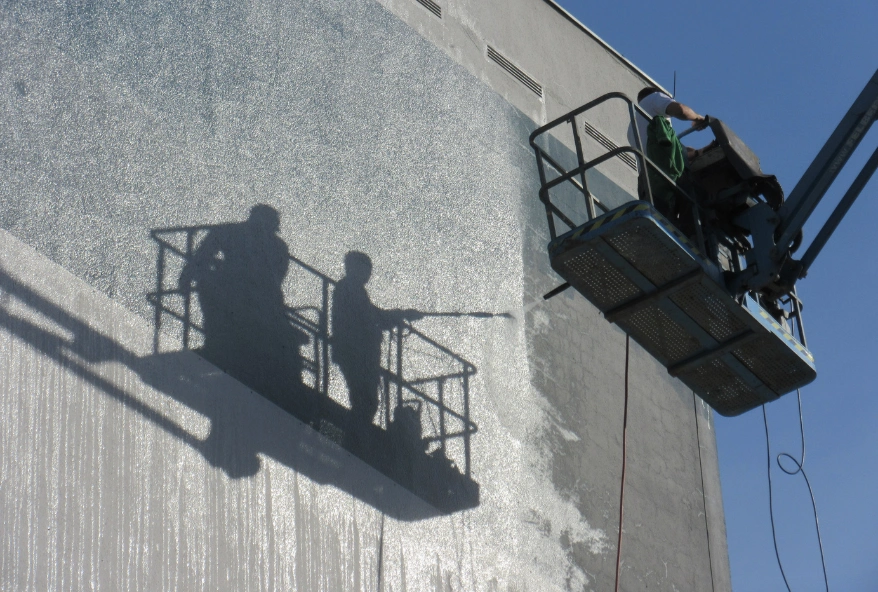 Worker cleaning a building facade using an elevated platform in Dubai